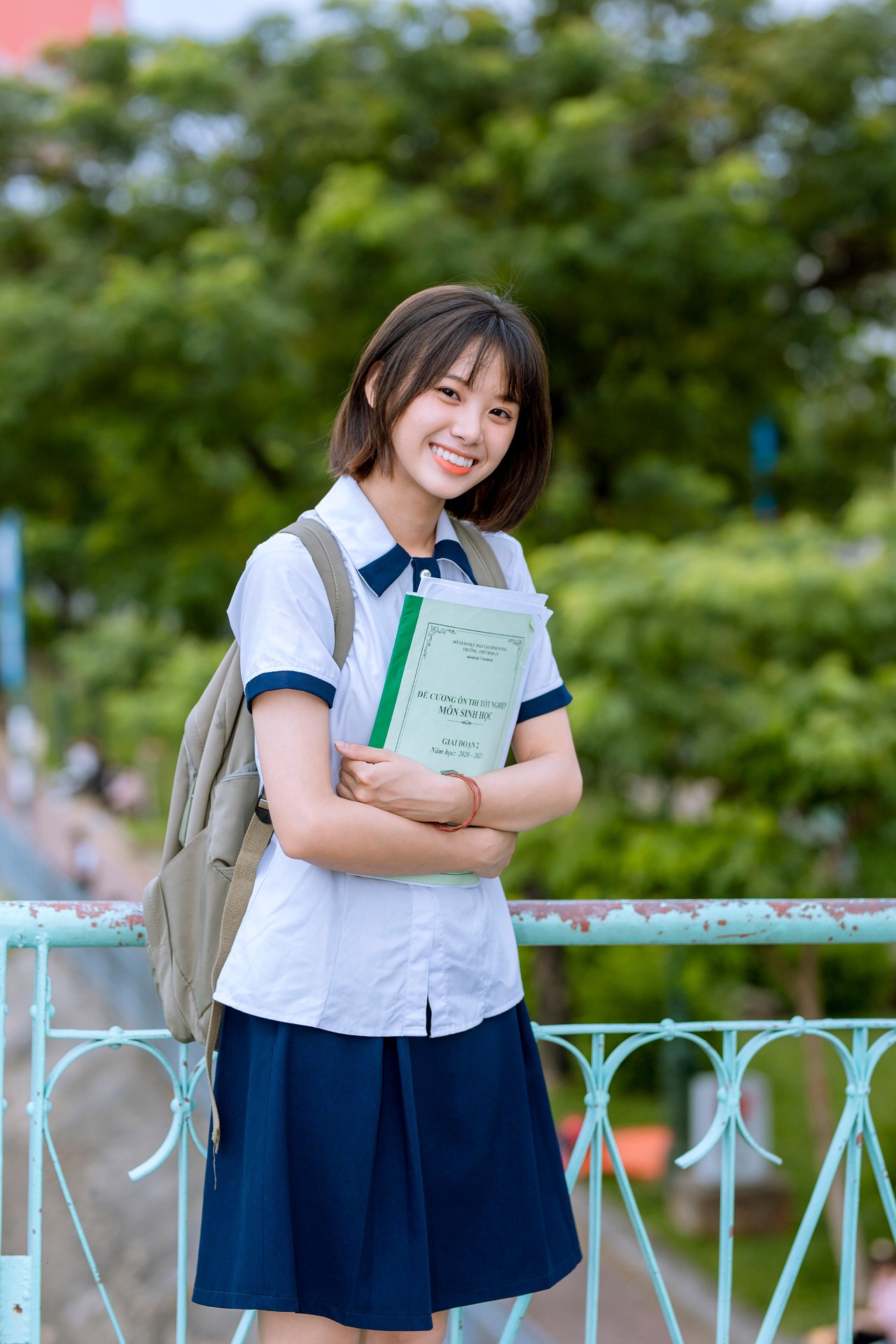 A high schooler smiling with her books and backpack, ready for the school year