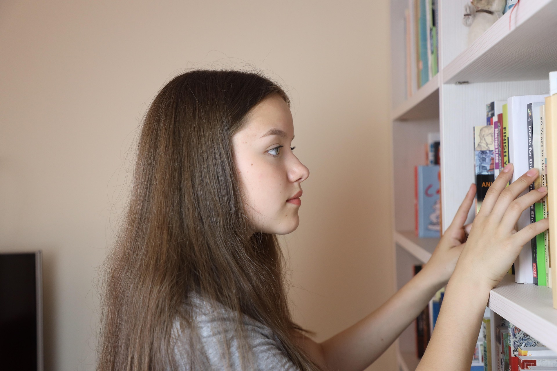 A homeschooled student choosing a book from her home library